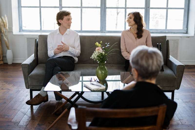 A man and woman talking on a couch during a therapy session focused on avoidant attachment healing.
