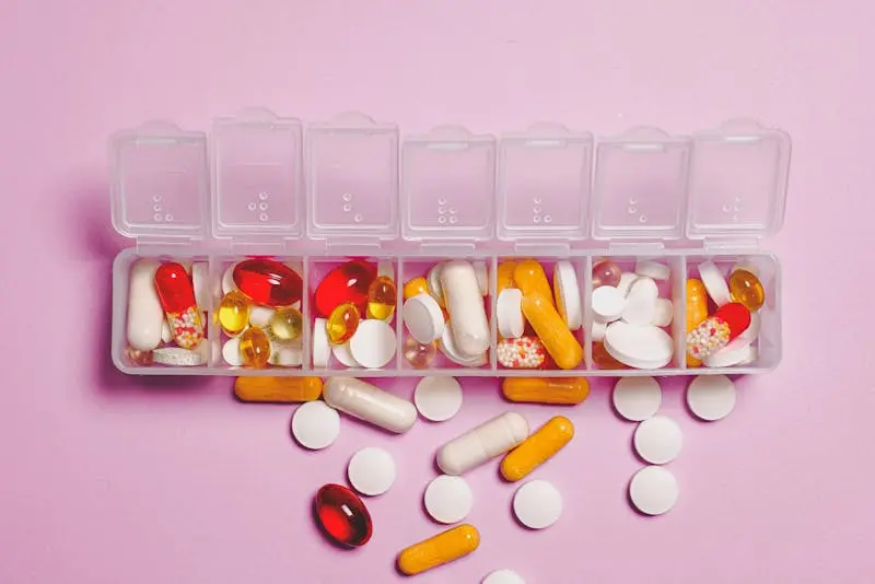 A clear plastic container filled with various colored pills and capsules, showcasing a range of medications.