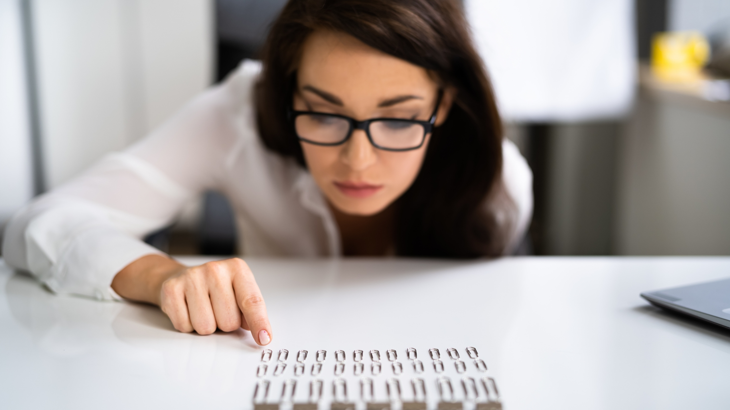 A woman wearing glasses intently gazes, focused on her work or research.