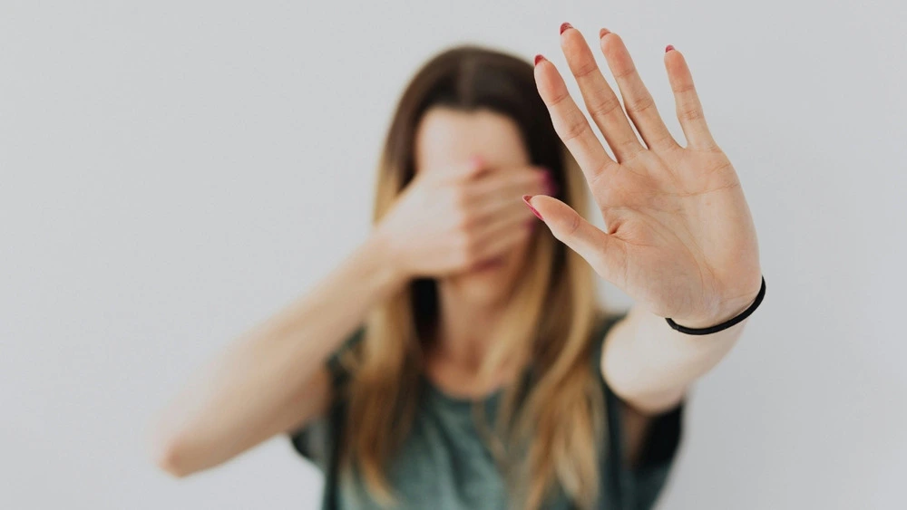 A woman with her hands over her eyes, suggesting a moment of reflection or emotional response.