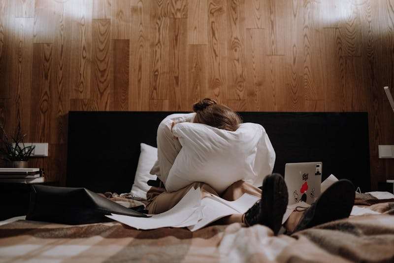 A person sitting on a bed looking emotionally distressed, reflecting feelings linked to abandonment depression.